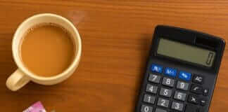 Monthly Budget Kaise Banaye? Step by Step Guide Hindi Mein Monthly Budget Kaise Banaye items including Indian currency, calculator, tea cup, and smartphone with budget app – flat lay for personal finance in India.